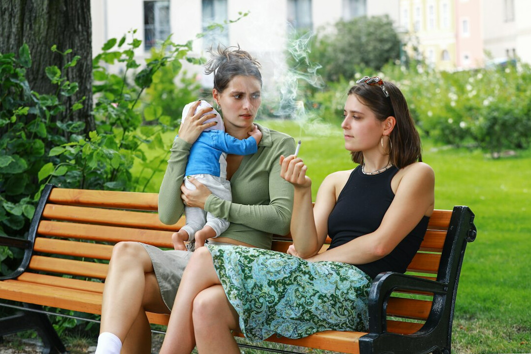 Adult daughter talking with her elderly mother at a table with tea